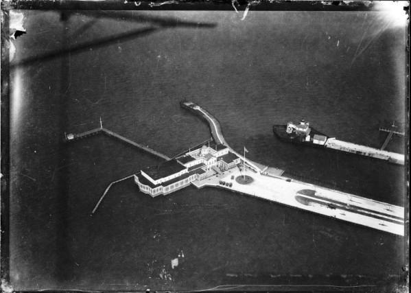 Black and white photo from above of a building on a man made point jutting out into a body of water.