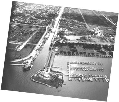 View from above of a canal opening onto a body of water, with a harbor visible.