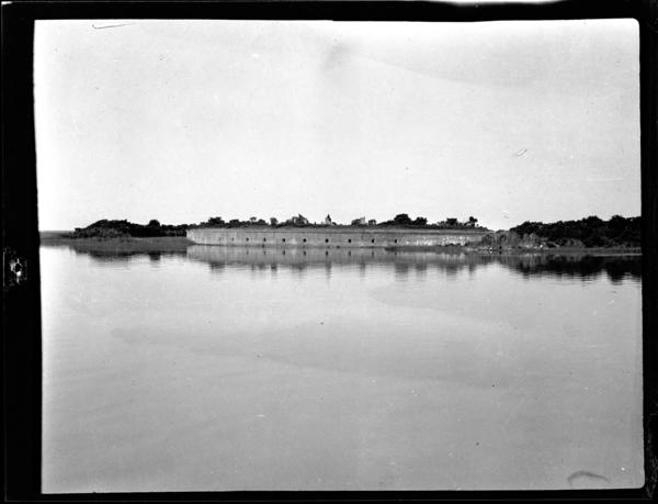 Black and white photo of a fort from across a body of water.