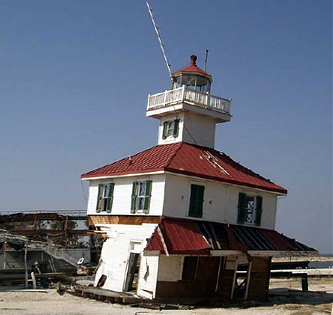 A tiered, white building with red roofs. It is damaged, leaning to the side and one corner is missing.